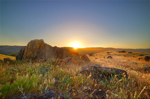 Sunrise over golden hillside and rocks