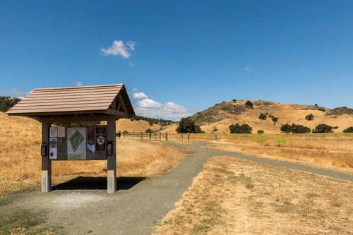 Trail kiosk at Coyote Valley Open Space Preserve with trail and golden hills