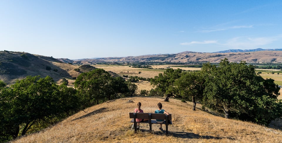 Two hikers sitting on bench overlooking Coyote Valley