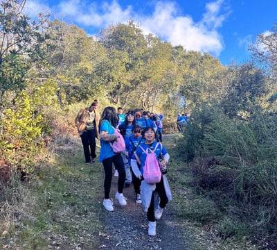 A group of children in blue Boys and Girls Club t-shirts on a hike.